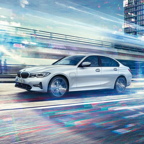 走行中のBMW 330eサイド・ビュー。G20 都市を背景に駆けぬけるBMW 330eのサイド・ビュー。G20