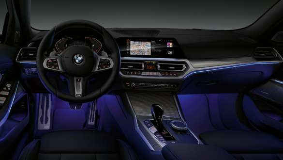 BMW 3シリーズ セダン(G20)、アンビエント・ライト。 アンビエント・ライトがレッグ・ルームをブルーに照らす、BMW 3シリーズ セダン(G20)運転席のコックピットのフロント・ビュー。