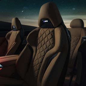 「メリノ」レザー製 M スポーツシート。F91 星空の下の BMW M8 Competition カブリオレ (ソフトトップを開けた状態)、「メリノ」レザー製 M スポーツシートと赤いアンビエントライトを備えたインテリア。F91