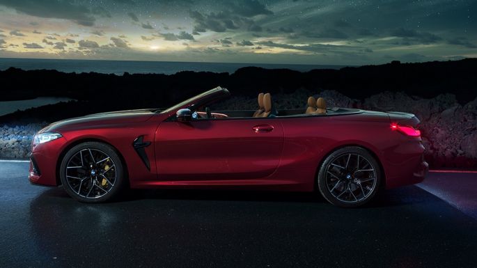 BMW M8 Competition カブリオレ、サイドビュー。F91 BMW M8 Competition カブリオレのモテギ・レッド・メタリックカラー (ソフトトップを開けた状態)、夜の星空の下でのサイドビュー。F91