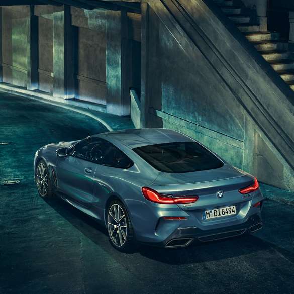 BMW M850i xDrive、左側から捉えたスリークォーターリアビュー。G15 BMW M850i xDriveクーペ(塗色バルセロナ ブルーメタリック)。夜間に停車中の車両を左側から捉えたスリークォーターリアビュー。G15
