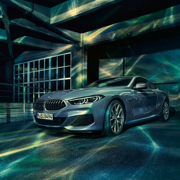 BMW M850i xDriveクーペ、スリークォーターフロントビュー。G15 BMW M850i xDriveクーペ(塗色バルセロナ ブルーメタリック)。ビルの前に停車したスリークォーターフロントビュー。G15