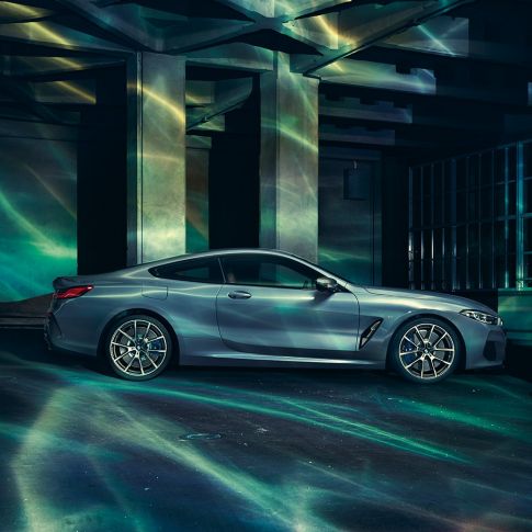 BMW M850i xDriveクーペ、サイドビュー。G15 BMW M850i xDriveクーペ(塗色バルセロナ ブルーメタリック)。ビルの前に停車中のサイドビュー。G15
