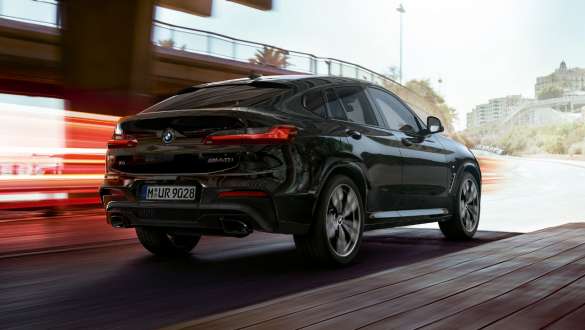 BMW X4 M40i、斜め向きリヤ・ビュー。F98 ブラック・サファイア・メタリックのBMW X4 M40i、走行中、エクステリア、ライト・ストリップの見える斜め向きリヤ・ビュー。F98