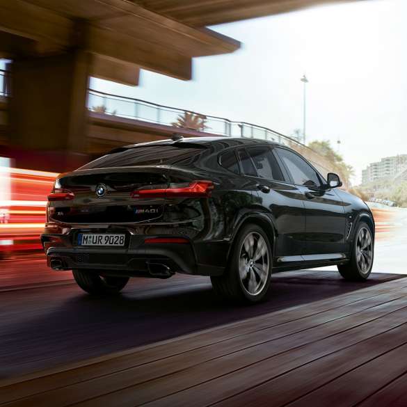 BMW X4 M40i、斜め前からのフロントビュー。 ブラック・サファイア・メタリックのBMW X4 M40i、走行中、エクステリア、ライト・ストリップの見える斜め前からのフロントビュー。