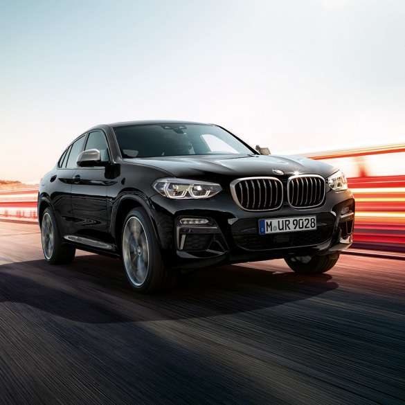 BMW X4 M40i、斜めリア・ビュー。F98 ブラック・サファイア・メタリックのBMW X4 M40i、走行中、エクステリア、ライト・ストリップの見える斜めリア・ビュー。F98