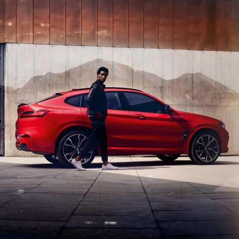BMW X4 M コンペティション、若い男性が映った側面画像。F98 トロント・レッド・メタリックのBMW X4 M コンペティション、エクステリア、若い男性が映った側面画像。F98