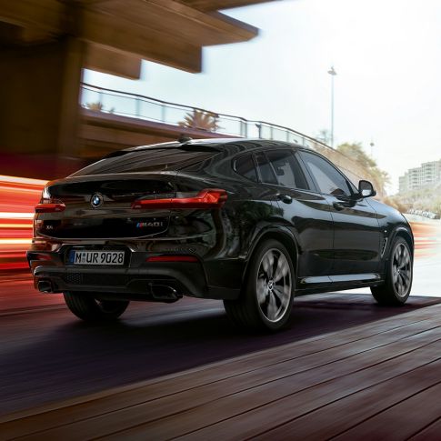 BMW X4 M40i、斜めからのリヤ・ビュー。F98 ブラック・サファイア・メタリックのBMW X4 M40i、エクステリア、斜めリヤ・ビュー、ライト・ストリップの見える右側面。F98