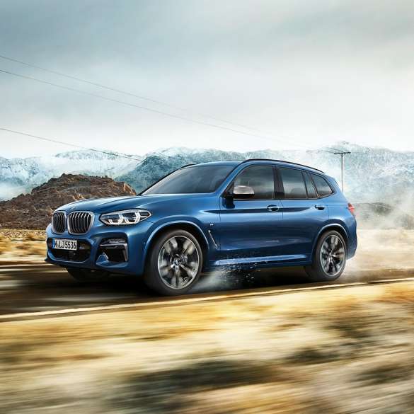 BMW X3 M40i、山を背景にしたミディアム・ショットのリムとフロント・フェンダー BMW X3 M40i、山を背景にしたミディアム・ショットのリムとフロント・フェンダー