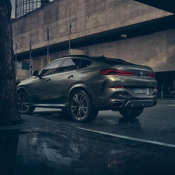 BMW X6のエクステリア。G06 BMW X6リアのスリークォータービュー、ある都市風景を背景に。G06