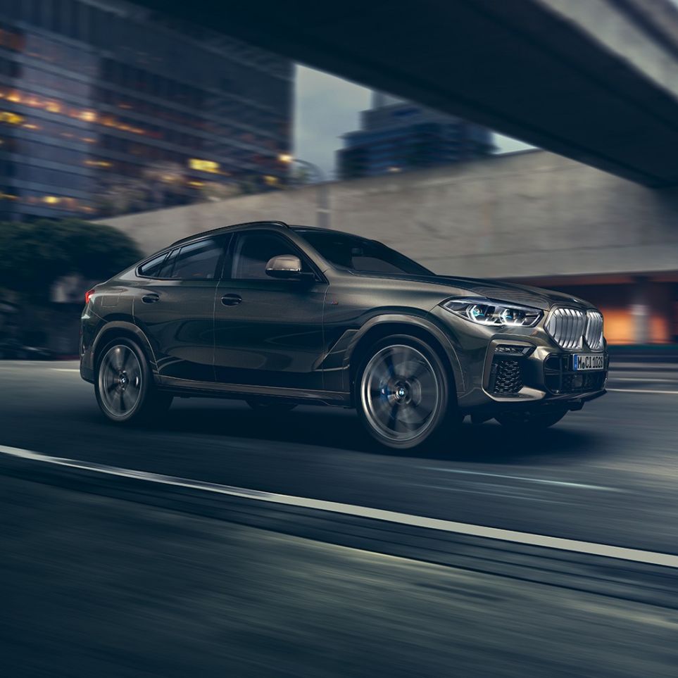 BMW X6のドライビング性能。G06 BMW X6フロントスリークォータービュー、ある都市風景を背景に。G06