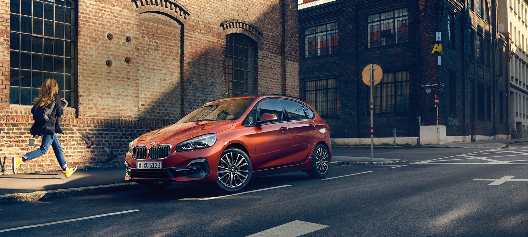 BMW 2シリーズ アクティブ ツアラー 駐車中 BMW 2シリーズ アクティブ ツアラーF45 サンセット・オレンジ・メタリック 斜めからのフロント・ビュー 路上に駐車中