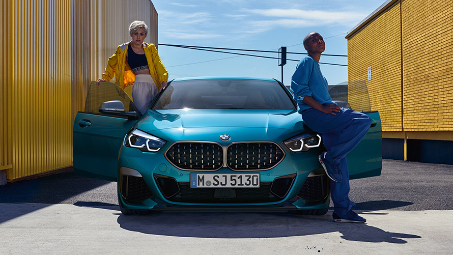 BMW 2シリーズ グラン クーペ(F44)、フロント・ビュー BMW 2 シリーズ グラン クーペ F44 スナッパー・ロック・ブルー、フロント・ビュー、ドアを開いた状態で2人の人物と一緒に