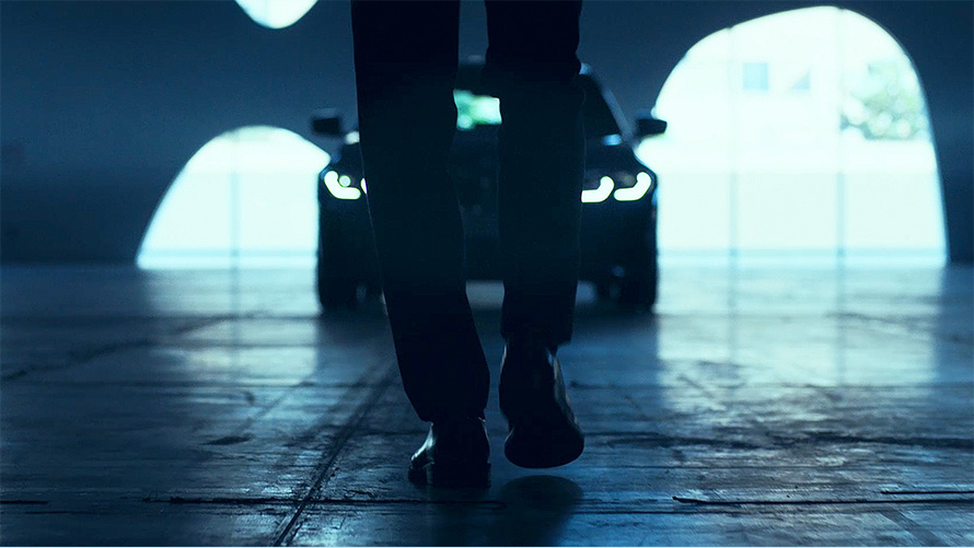 BMW 3シリーズ セダン(G20)、フロント。 BMW 3シリーズ セダン(G20)の前でアスファルトの上を歩く男性の後ろからのビュー。