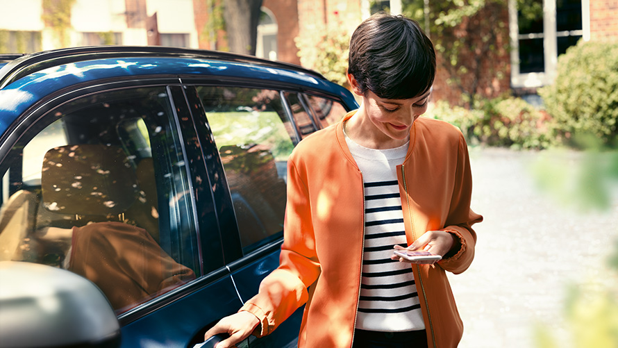 BMWサービス 女性がBMWの隣でスマートフォンを見ている BMWサービス 女性がBMWの隣でスマートフォンを見ている