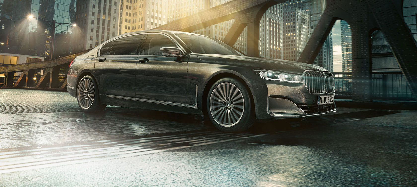 BMW 7 シリーズ セダンの側面ビュー 照明の当たったホテルの前に停車しドアを開いたBMW 7 シリーズ セダンの側面ビュー