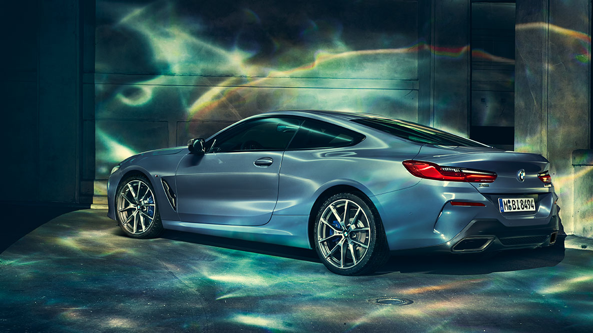BMW 8シリーズ・クーペ、斜めからのリヤ・ショット。 夜の都会を背景にしたBMW 8シリーズ クーペの斜めからのリヤ・ショット。