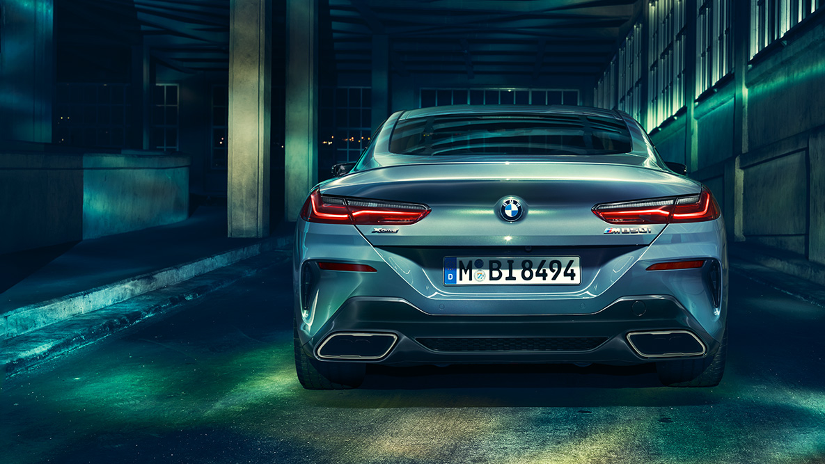 BMW 8シリーズ クーペ、リヤ・ビュー。 夜の都会を背景にしたBMW 8シリーズ クーペのリヤ・ビュー。