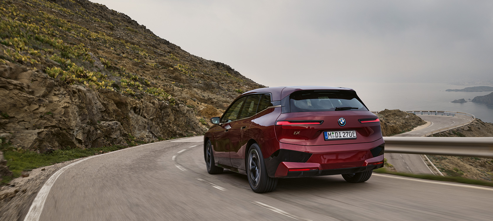 海岸通りを走行するBMW iX i20 電気自動車 2021電動SUV BMW iX xDrive50 海岸通りを走行するBMW iX i20 電気自動車 2021電動SUV BMW iX xDrive50アベンチュリン・レッドの背面