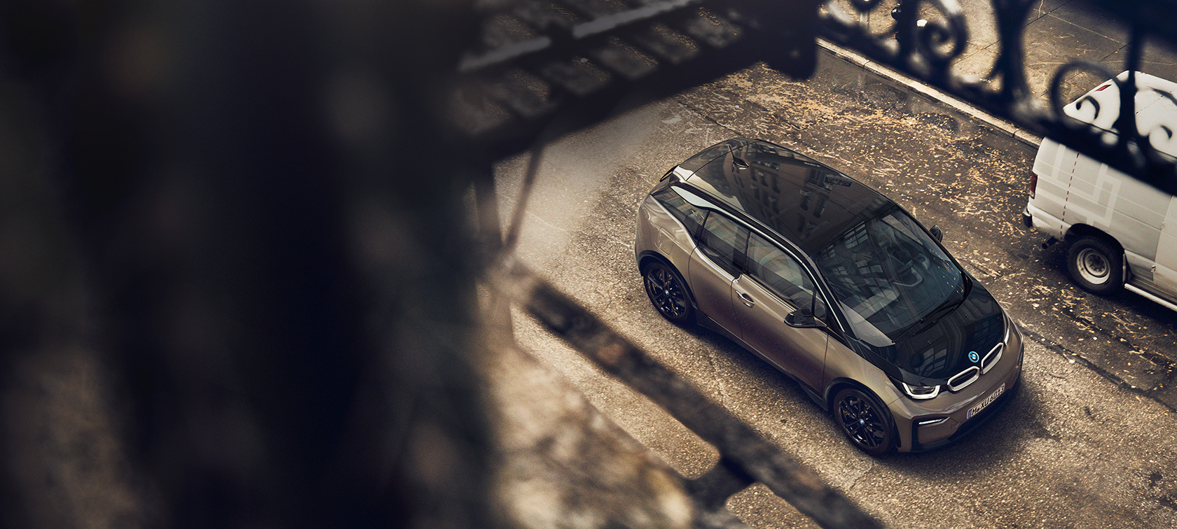 BMW i3s 2018 ガレージを背景に BMW i3s I01 2018 フルイド・ブラック BMW iブルー・ハイライト付 斜めからのリヤ・ビュー BMWウォールボックスのあるガレージを背景に