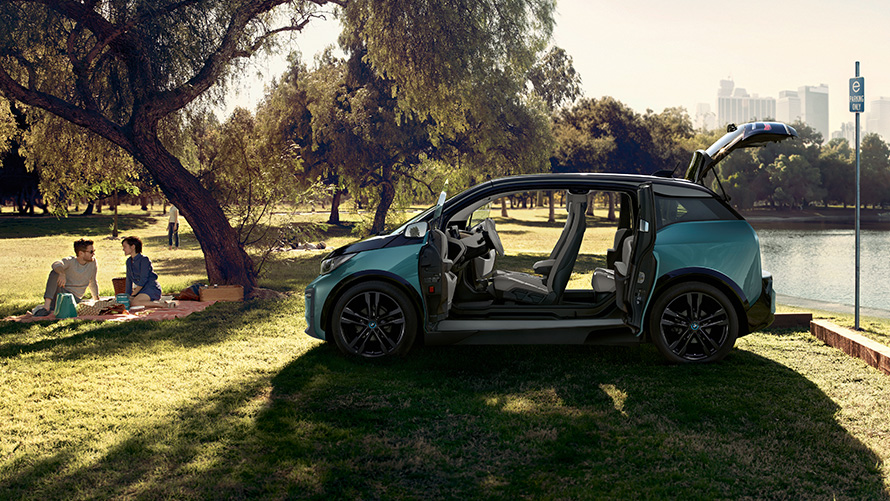公園でのBMW i3 2018 BMW i3 I01 2018 フカロ・ベージュ フローズン・グレー・メタリック・ハイライト付 公園でドアが開いた状態のサイド・ビュー