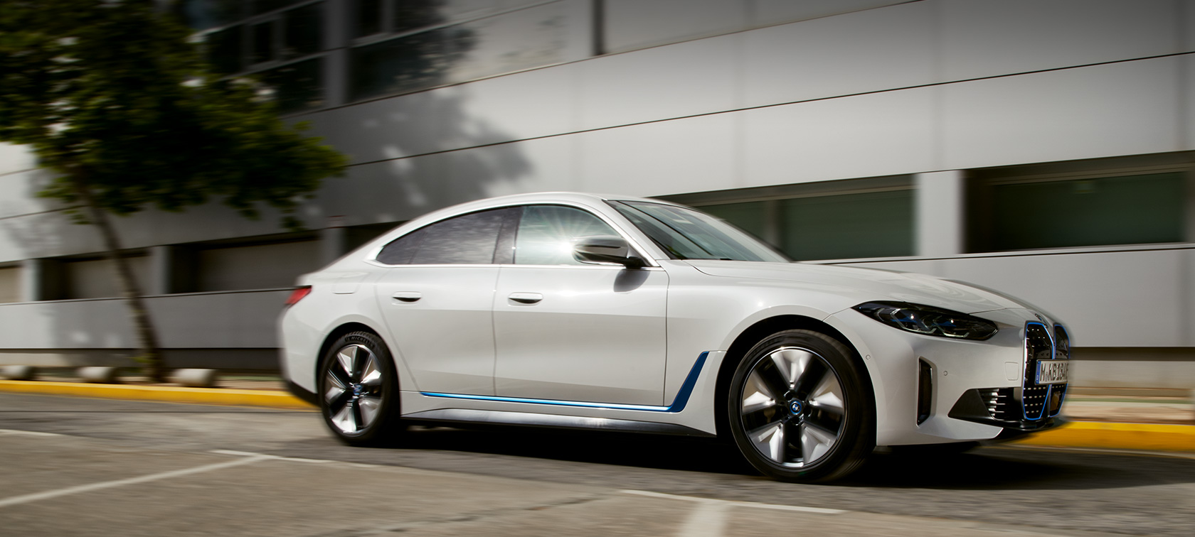 BMW i4 eDrive40 G26 電気自動車 2021 斜めからのサイド・ビュー 建物の前を走行中 BMW i4 eDrive40 G26 電気自動車 2021 斜めからのサイド・ビュー 建物の前を走行中