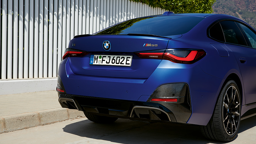 BMW i4 M50 G26 電気自動車 2021 BMW Individual フローズン・ポルティマオ・ブルー・メタリック 斜めからのリヤ・ビュー 白いフェンスのそばに停車