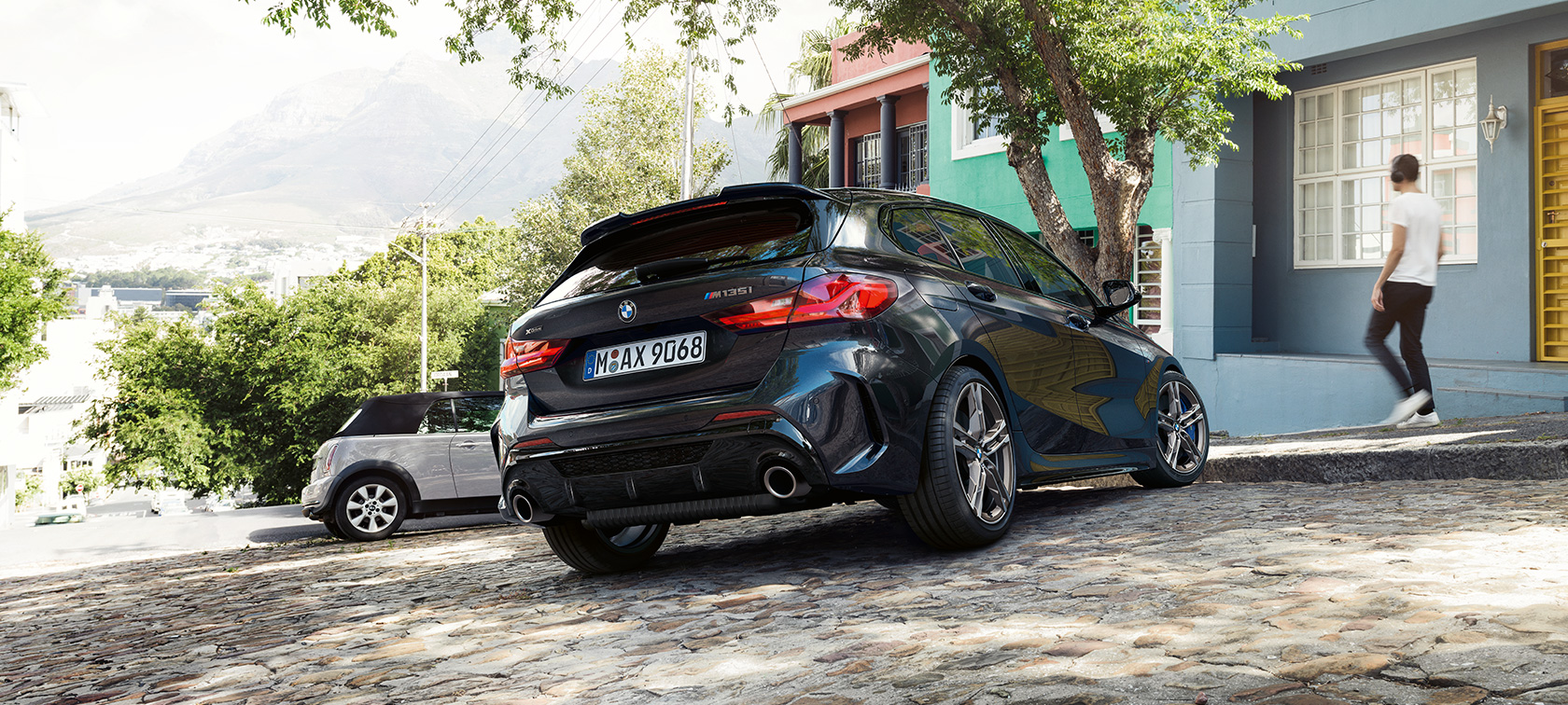 BMW M135i xDrive、斜め後ろからのショット。 F40 BMW M135i xDrive、ブラック・サファイア・メタリック、停車時、住宅を背景にした斜め後ろからのショット。 F40