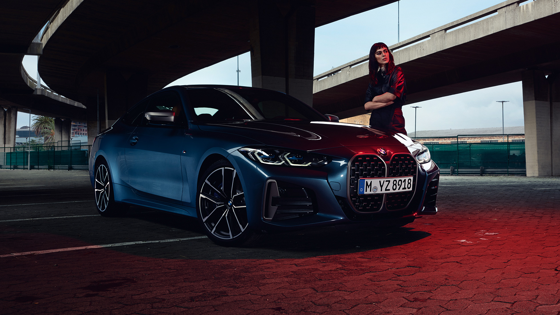 BMW M440i xDrive クーペ G22 2020の横にモデルが立っている斜めからのサイド・ビュー BMW M440i xDrive クーペ、アークティック・レース・ブルー・メタリック G22 2020 - 斜めからのサイド・ビュー、モデルと共に