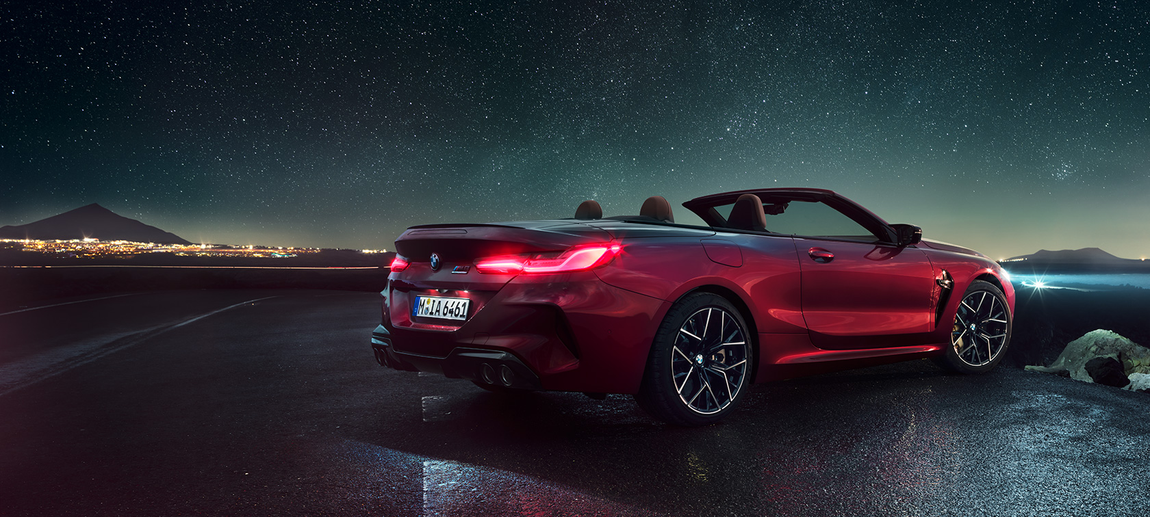 BMW M8 COMPETITION カブリオレ、スリークウォーター・リアビュー。 BMW M8 Competition カブリオレのモテギ・レッド・メタリックカラー (ソフトトップを開けた状態)、星空の下でのスリークウォーター・リアビュー。