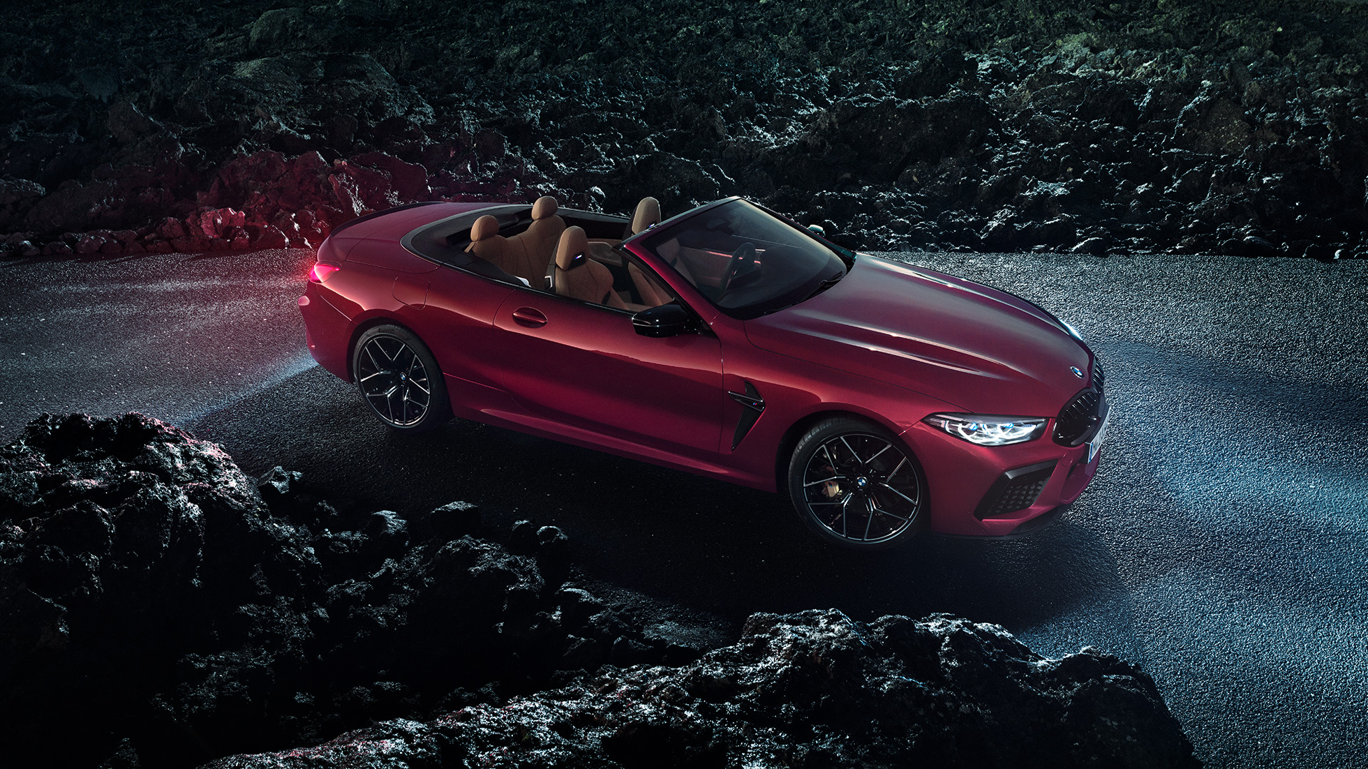 BMW M8 Competition カブリオレ、スリークウォーター・サイドビュー。F91 BMW M8 Competition カブリオレのモテギ・レッド・メタリックカラー (ソフトトップを開けた状態)、夜のアスファルト上でのスリークウォーター・サイドビュー。F91