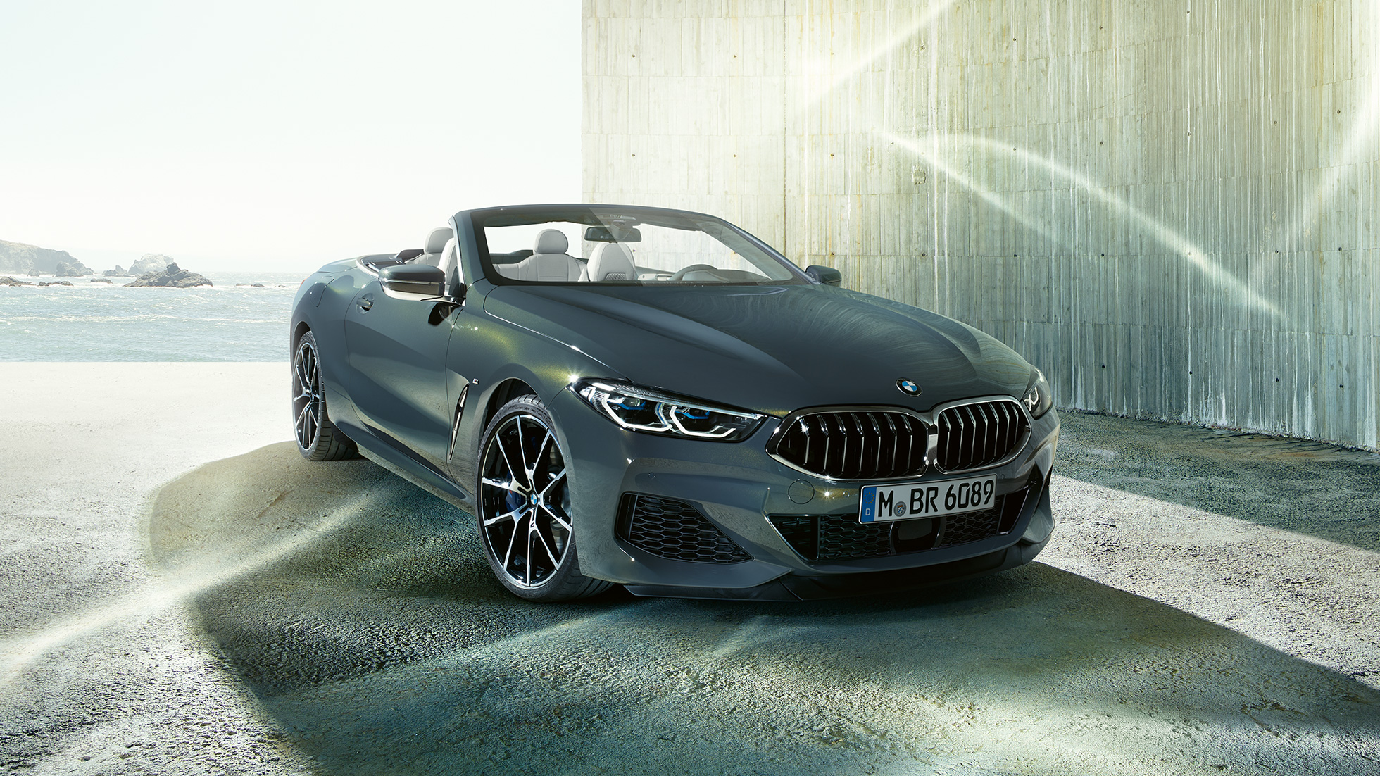 BMW M850i xDrive カブリオレ、スリークォータービュー。G14 BMW M850i xDrive カブリオレ (ソフトトップを開けた状態)、海岸を背景にしたスリークォータービュー。G14