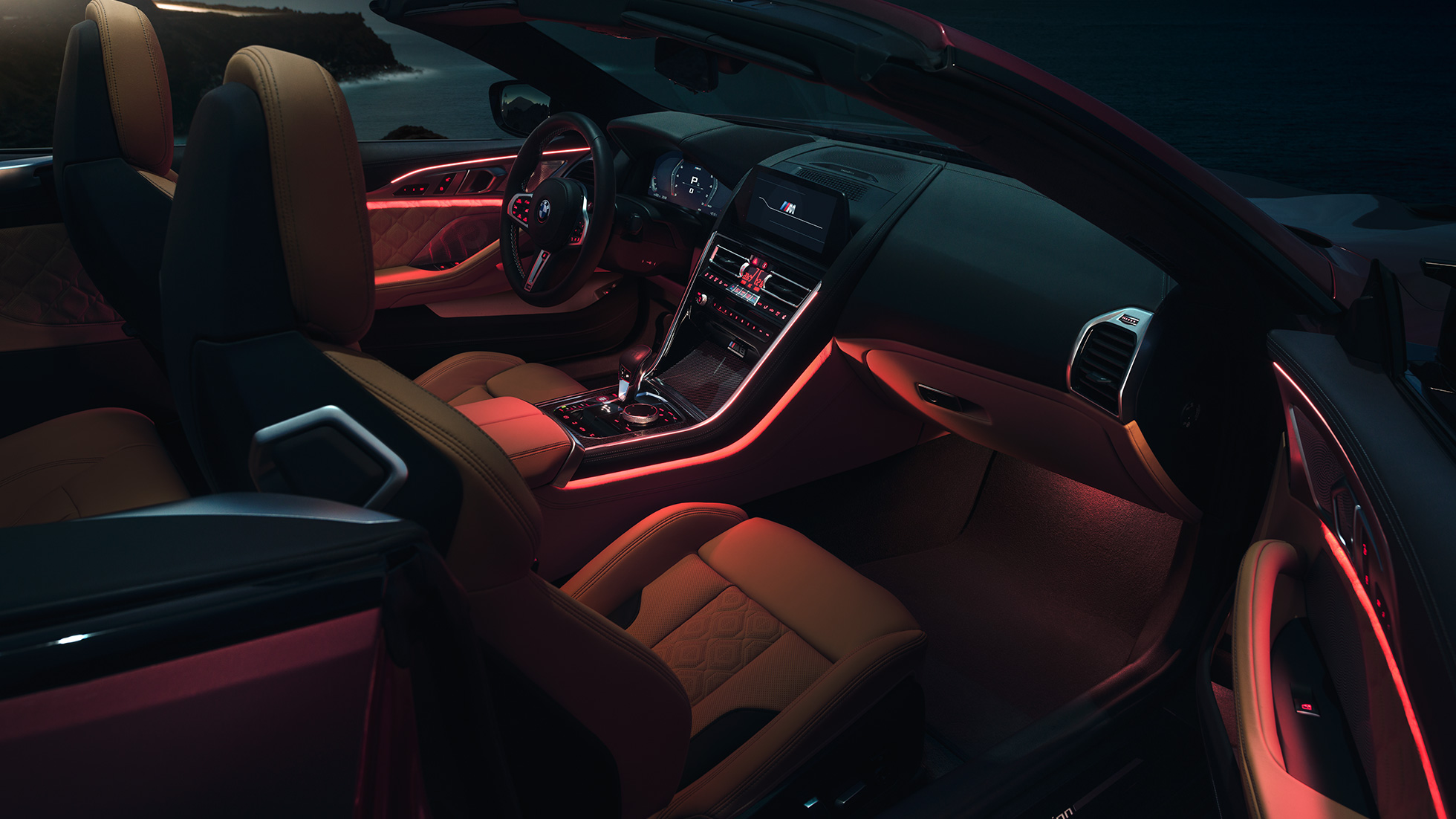 BMW M8 Competition カブリオレ、インテリア。F91 BMW M8 Competition カブリオレ (ソフトトップを開けた状態)、赤いアンビエントライトが光る夜間のインテリア。F91