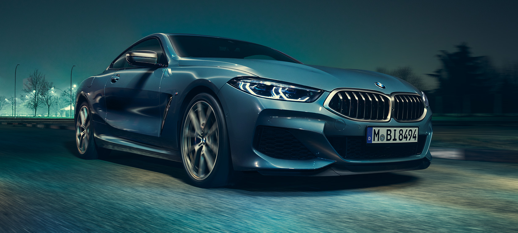 BMW M850i xDriveクーペ、スリークォーターフロントビュー。 BMW M850i xDriveクーペ(塗色はバルセロナ ブルーメタリック)、疾走する車両のスリークォーターフロントビュー。