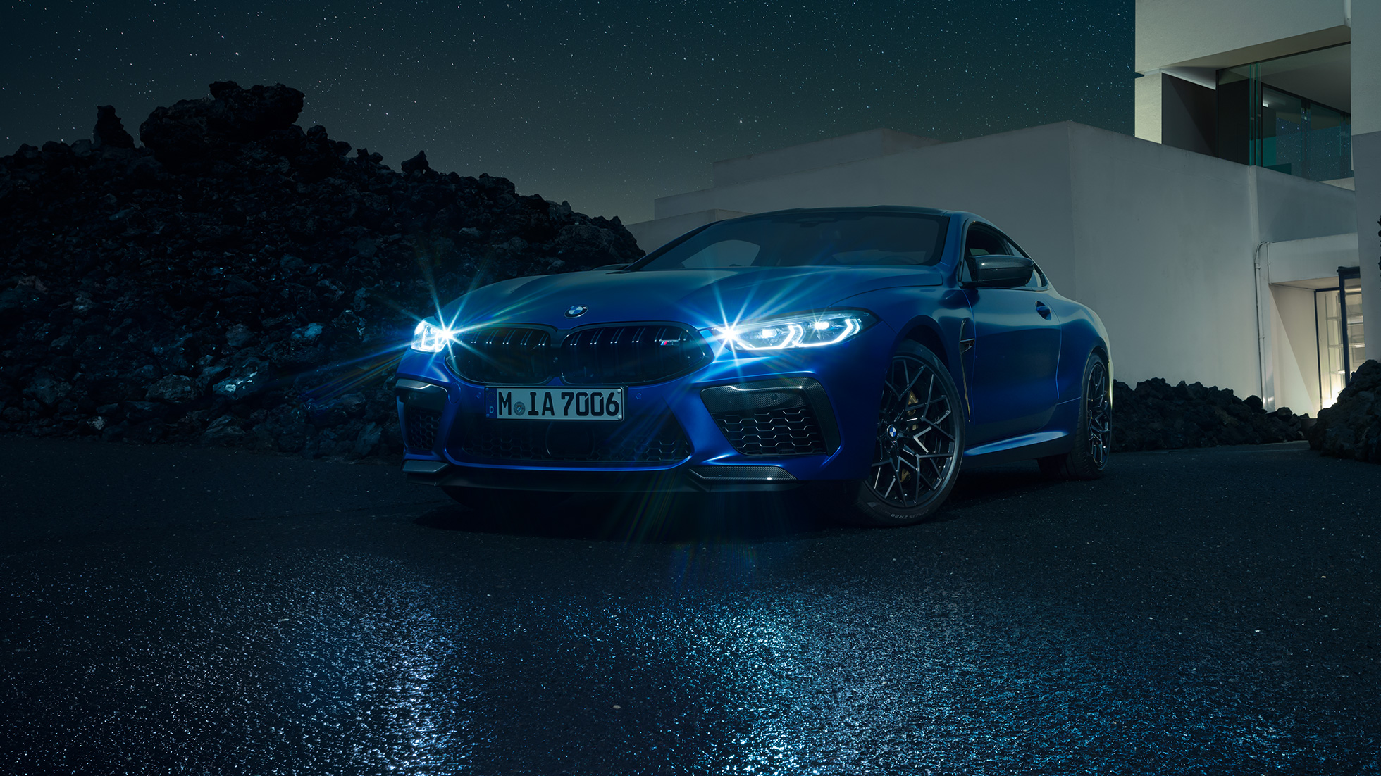 BMW M8 コンペティションクーペ、スリークォーターフロントビュー。F92 BMW M8 コンペティションクーペ(塗色マリーナベイ ブルーメタリック)。邸宅の前に停車中。きらめくLEDヘッドライトが印象的なスリークォーターフロントビュー。F92