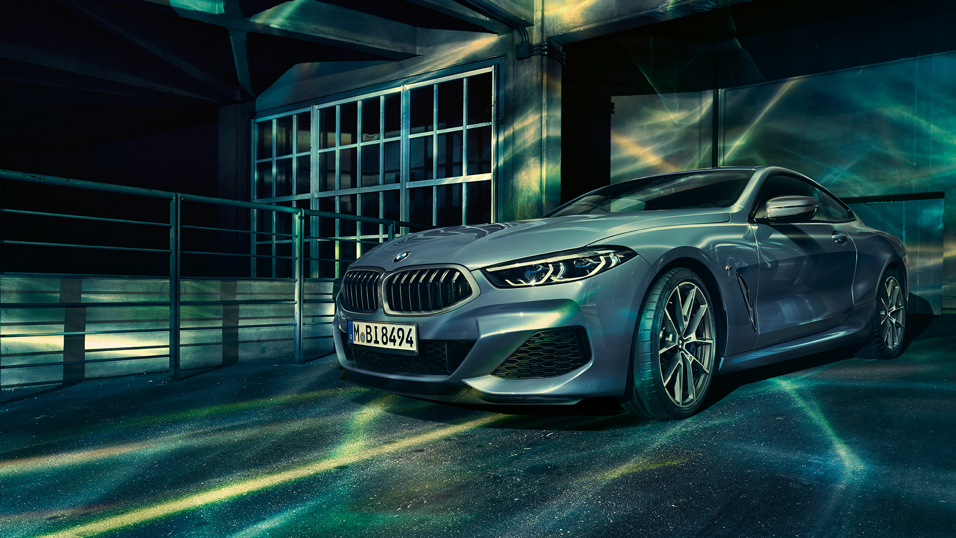 BMW M850i xDriveクーペ、スリークォーターフロントビュー。G15 BMW M850i xDriveクーペ(塗色バルセロナ ブルーメタリック)。ビルの前に停車したスリークォーターフロントビュー。G15