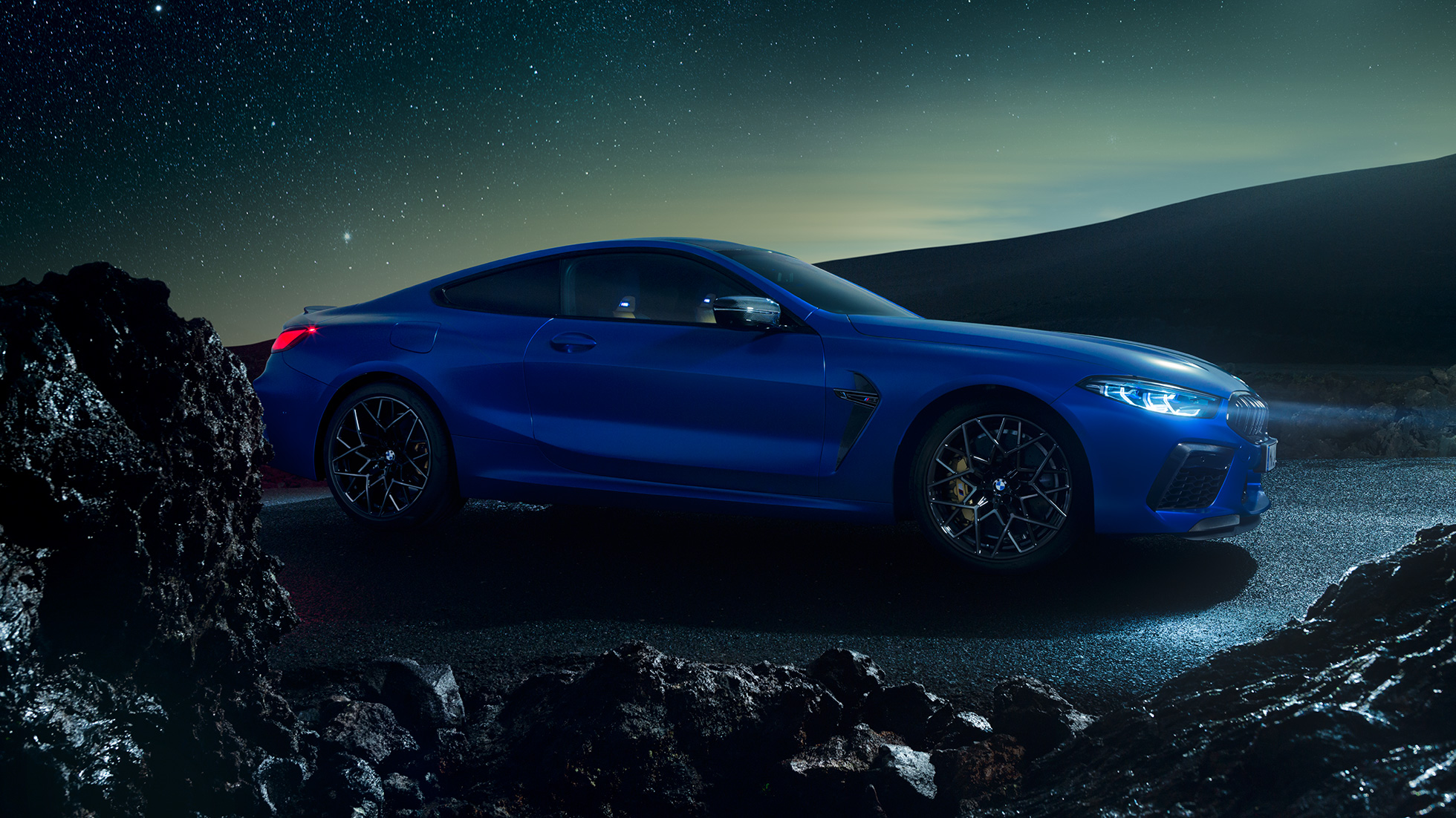 BMW M8 コンペティションクーペ、スリークォーターサイドビュー。F92 BMW M8 コンペティションクーペ(塗色マリーナベイ ブルーメタリック)。夜間に停車中のスリークォーターサイドビュー。F92