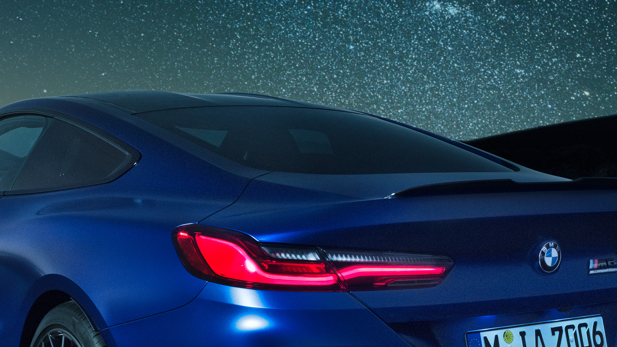 Mリアスポイラー F92 BMW M8 コンペティションクーペ(塗色マリーナベイ ブルーメタリック)。夜間におけるショルダー部のクロースアップビュー。カーボンのMリアスポイラーが見える。F92