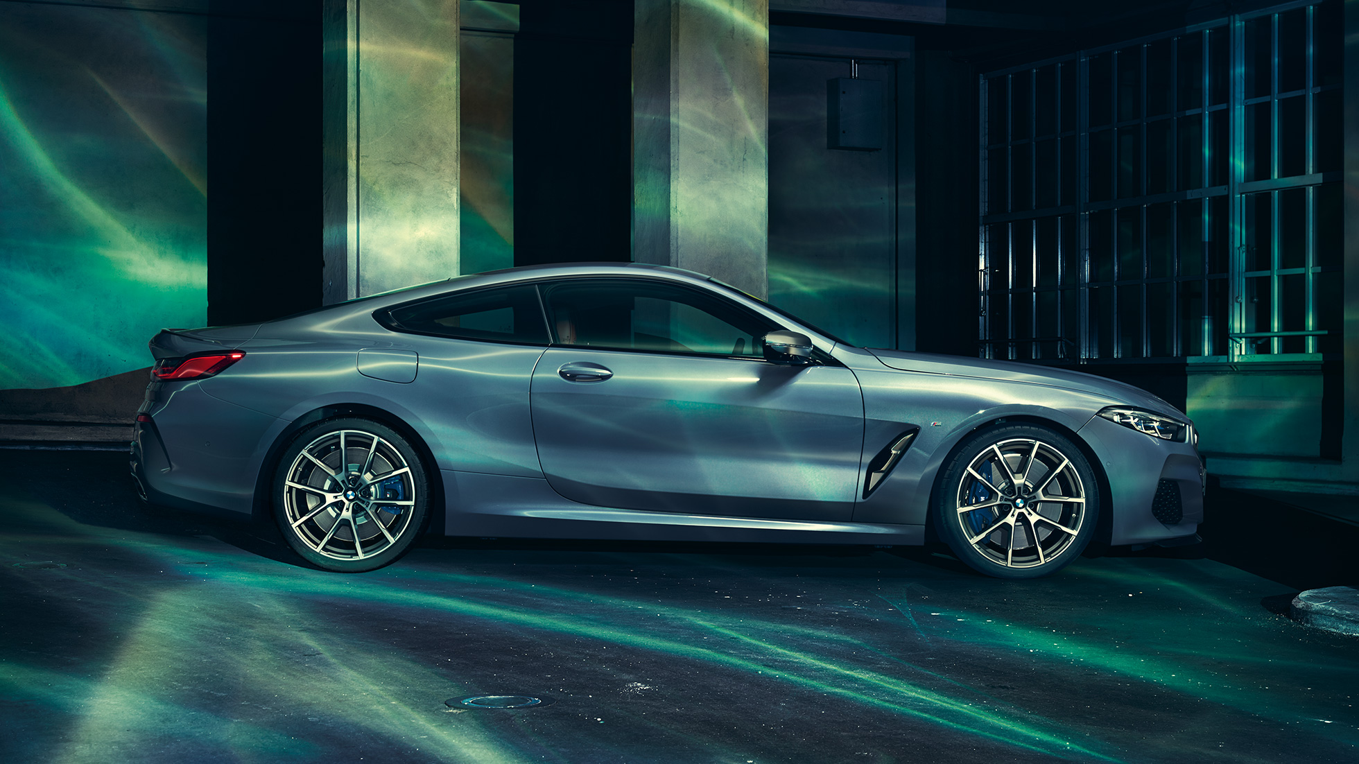 BMW M850i xDriveクーペ、サイドビュー。G15 BMW M850i xDriveクーペ(塗色バルセロナ ブルーメタリック)。ビルの前に停車中のサイドビュー。G15