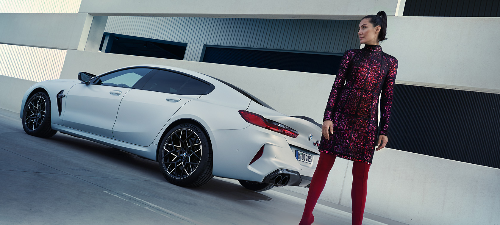 斜めからのリヤ・ビュー BMW M8 Competition グラン クーペ F93 LCI 2022 BMW M8 Competition グラン クーペ F93 LCI フェイスリフト 2022 BMW Individualフローズン・ブリリアント・ホワイト・メタリック 斜めからのリヤ・ビュー 横に立つ女性モデルとともに