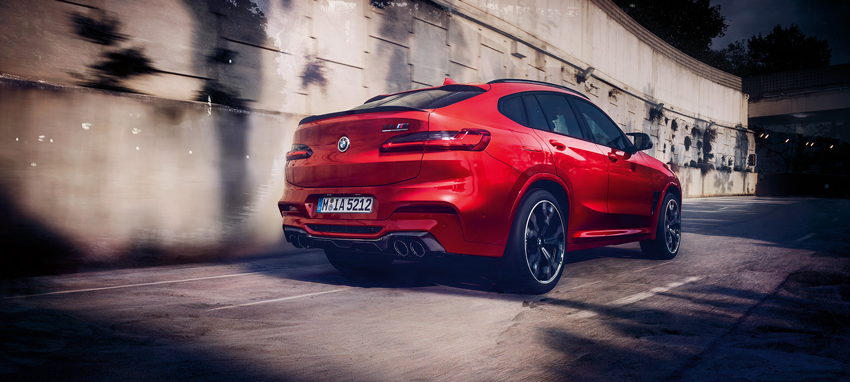 BMW X4 M コンペティション、斜めからのリア・ビュー。F98 トロント・レッド・メタリックのBMW X4 M コンペティション、走行中、エクステリア、斜めからのリア・ビュー。F98