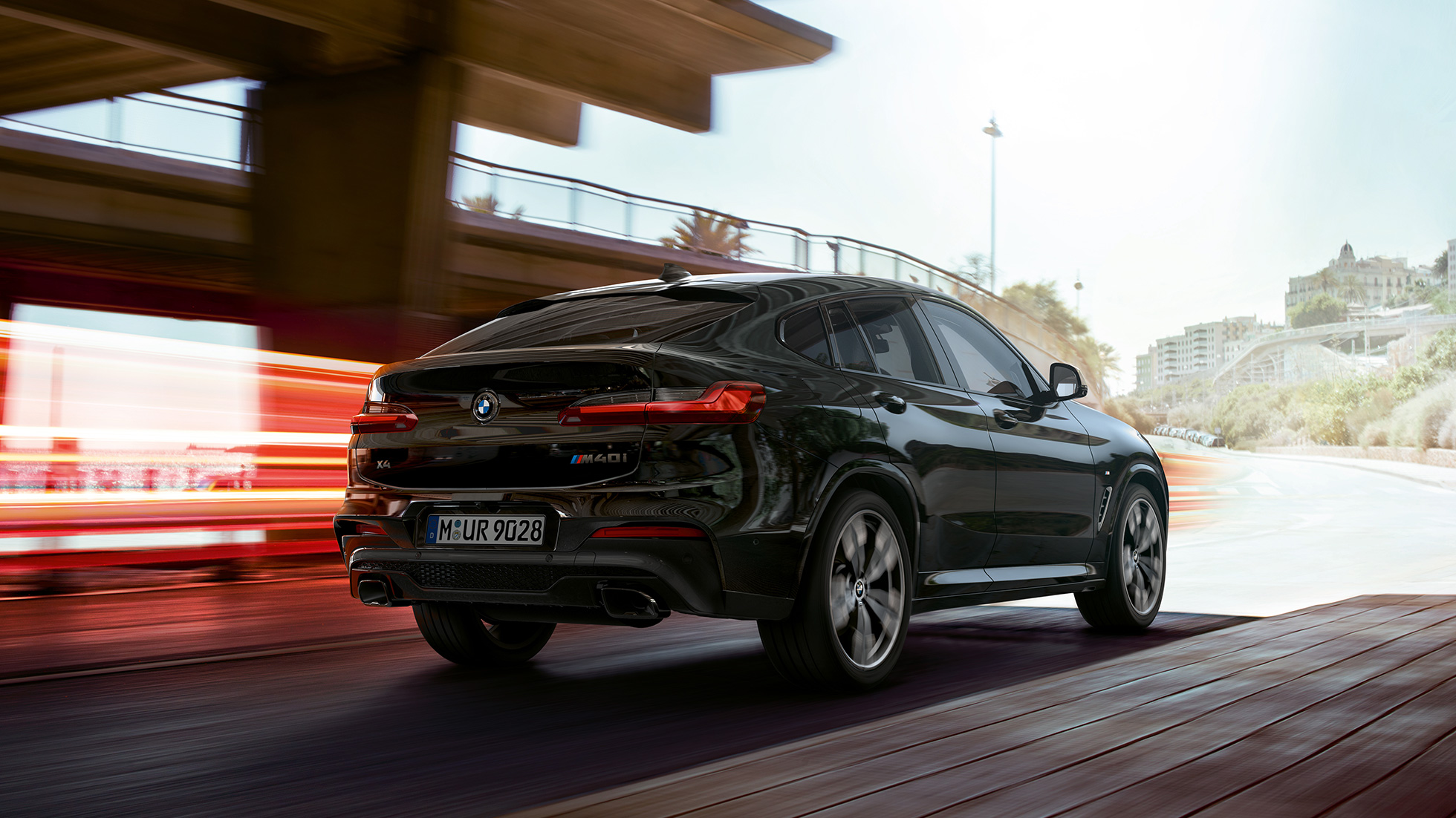 BMW X4 M40i、斜め前からのフロントビュー。F98 ブラック・サファイア・メタリックのBMW X4 M40i、走行中、エクステリア、ライト・ストリップの見える斜め前からのフロントビュー。F98