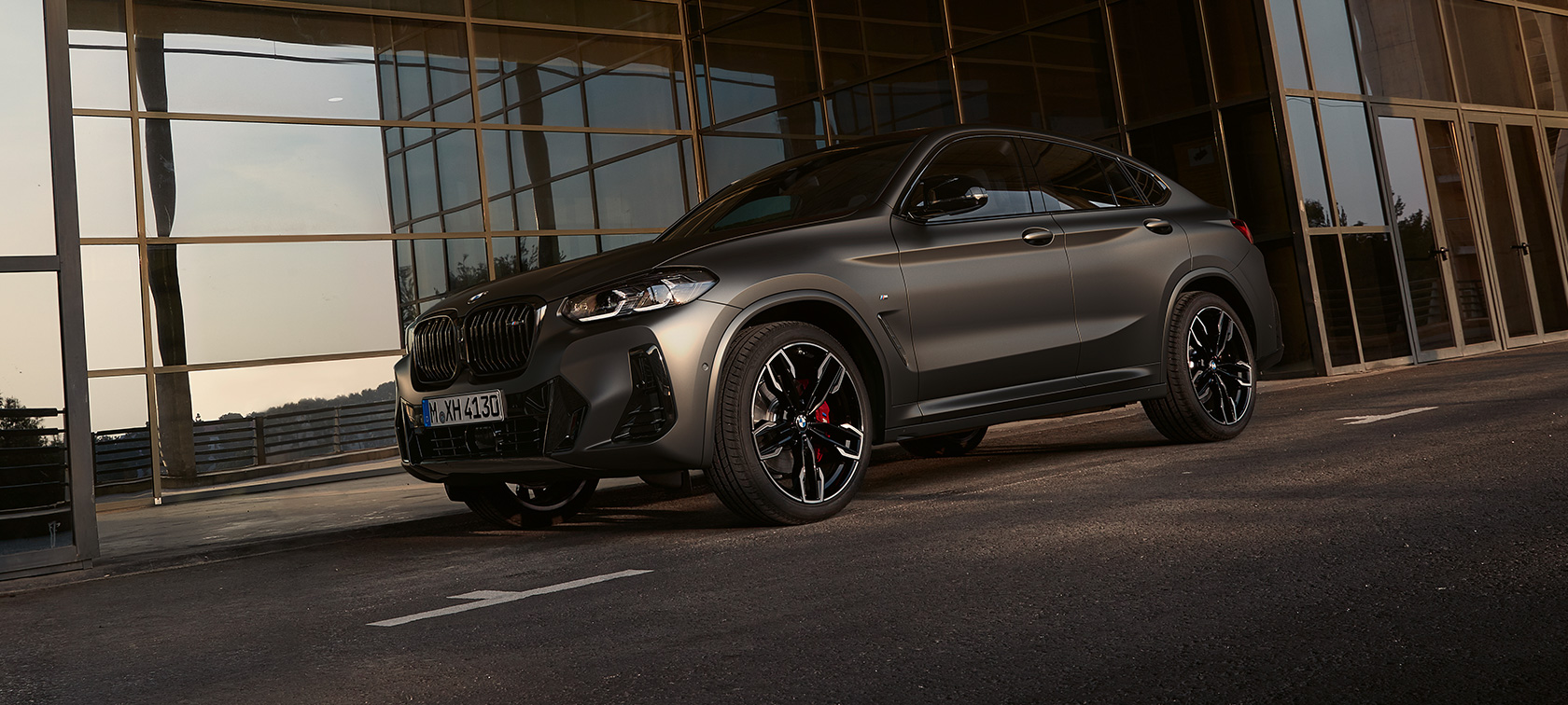 斜めからのフロント・ビュー BMW X4 M40i G02 LCI 2021フェイスリフト BMW X4 M40i G02 LCIフェイスリフト2021 斜めからのフロント・ビュー ガラス・ファサードを背景にして