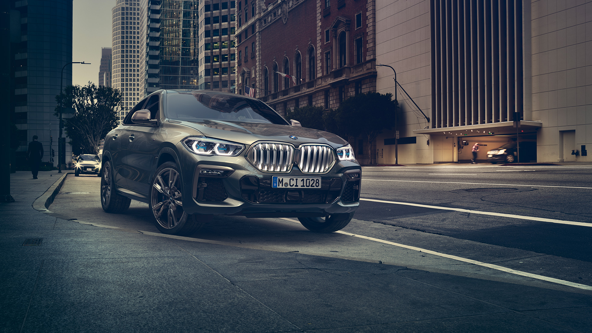 静止中のBMW X6 M50i 都会的な風景を背景にした、斜め前からのBMW X6 M50i