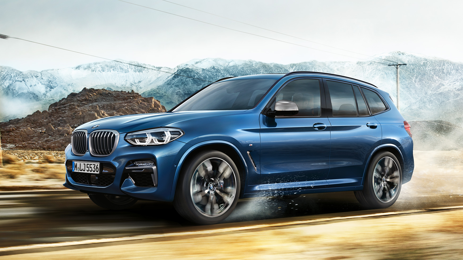 BMW X3 M40i、山を背景にしたミディアム・ショットのリムとフロント・フェンダー BMW X3 M40i、山を背景にしたミディアム・ショットのリムとフロント・フェンダー