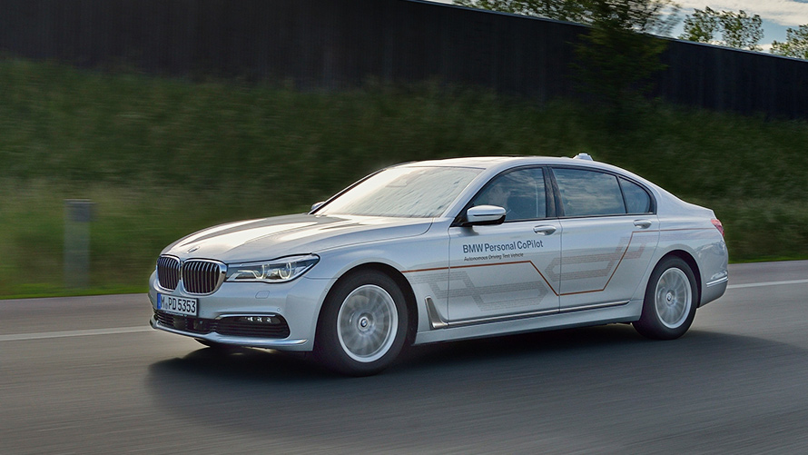 グレーの BMW 7 シリーズ・セダン スカイラインを背景に橋の上を走るグレーの BMW 7 シリーズ・セダン