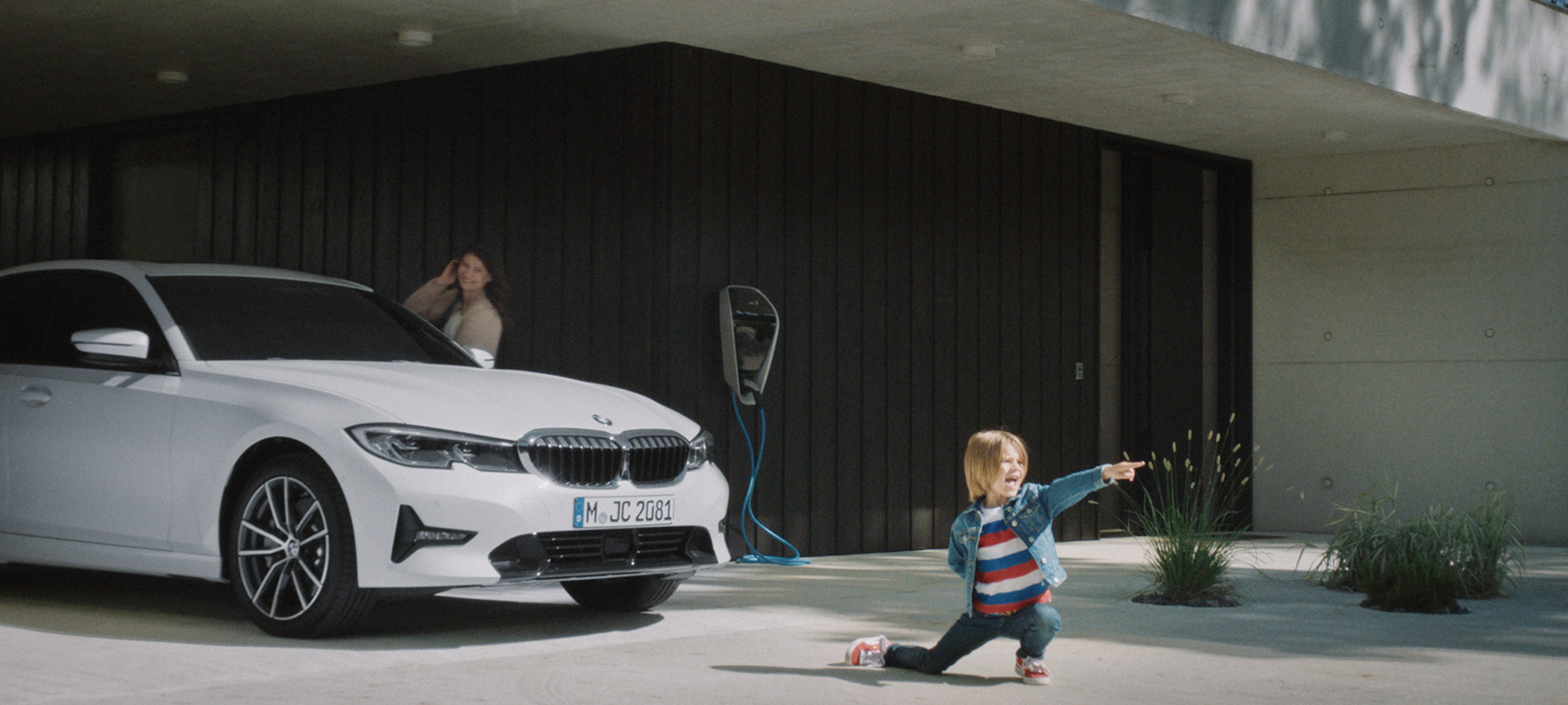 充電ステーションに佇むBMWハイブリッド車 BMWプラグイン・ハイブリッド 充電ステーションに停まるBMWハイブリッド車の前に佇む少年