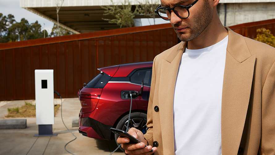 BMW iXの前でスマートフォンを持つ男性 充電ステーションにて BMW iXの前でスマートフォンを持つ男性 充電ステーションにて