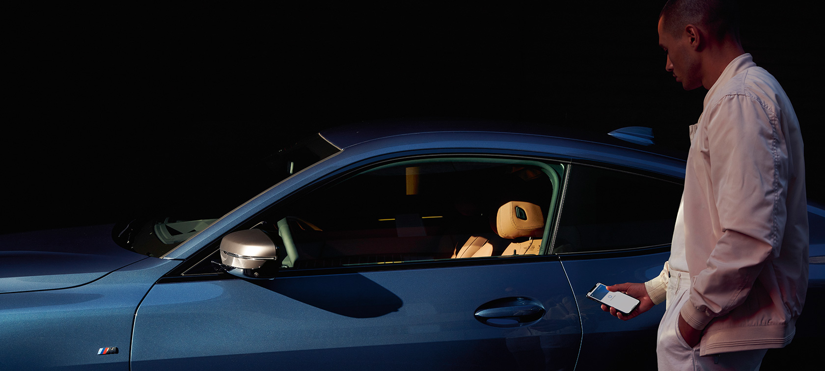 BMWデジタル・キー BMWデジタル・キー My BMW App 男性がスマートフォンでBMW 4シリーズ・クーペを解錠します