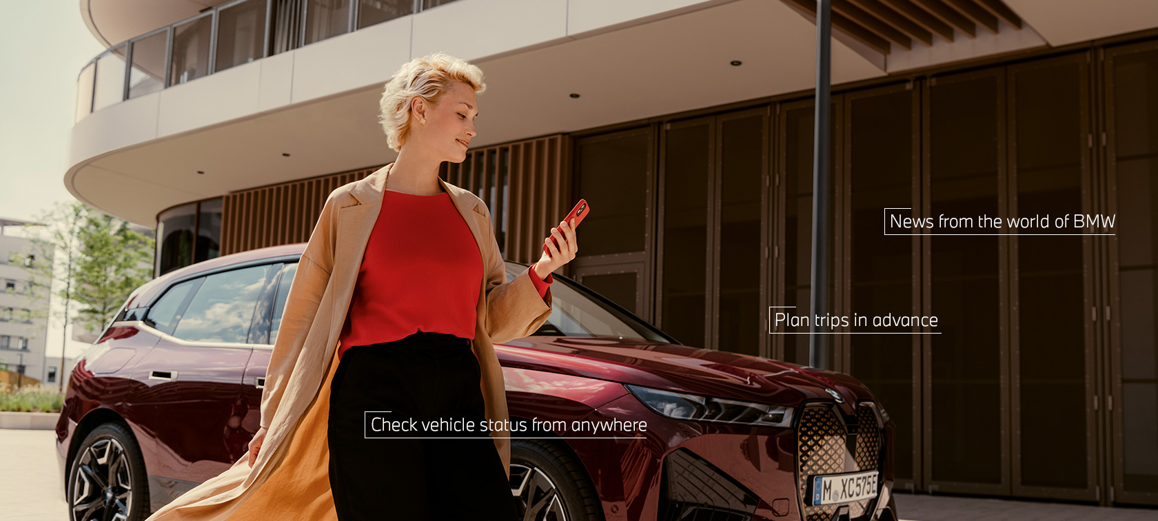 スマートフォンのMy BMWアプリを使っているBWW iXの前にいる女性 スマートフォンのMy BMWアプリを使っているBWW iXの前にいる女性